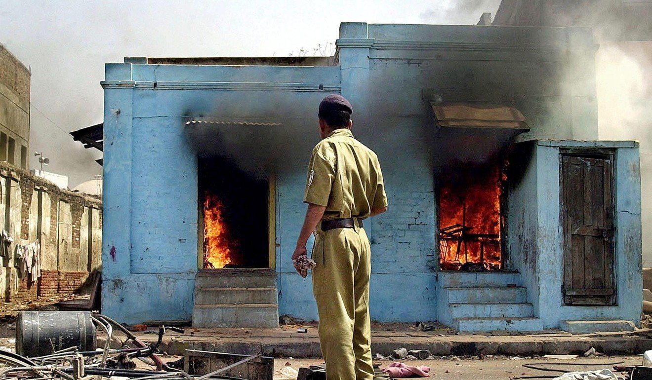 A policeman watches on as fire ravages shops at the entrance to a mosque in Ahmedabad, Gujarat, following an attack by Hindu activists in February 2002. Photo: AFP