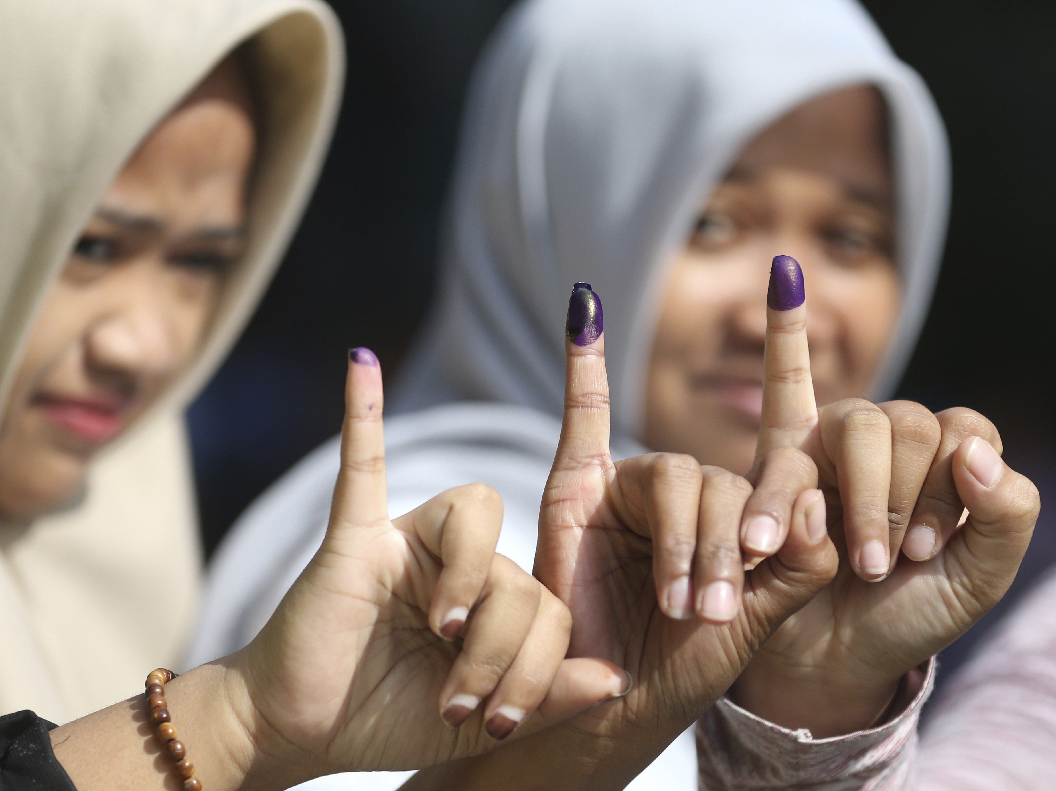 Muslim women show their ink-stained fingers after voting in Jakarta. Photo: AP