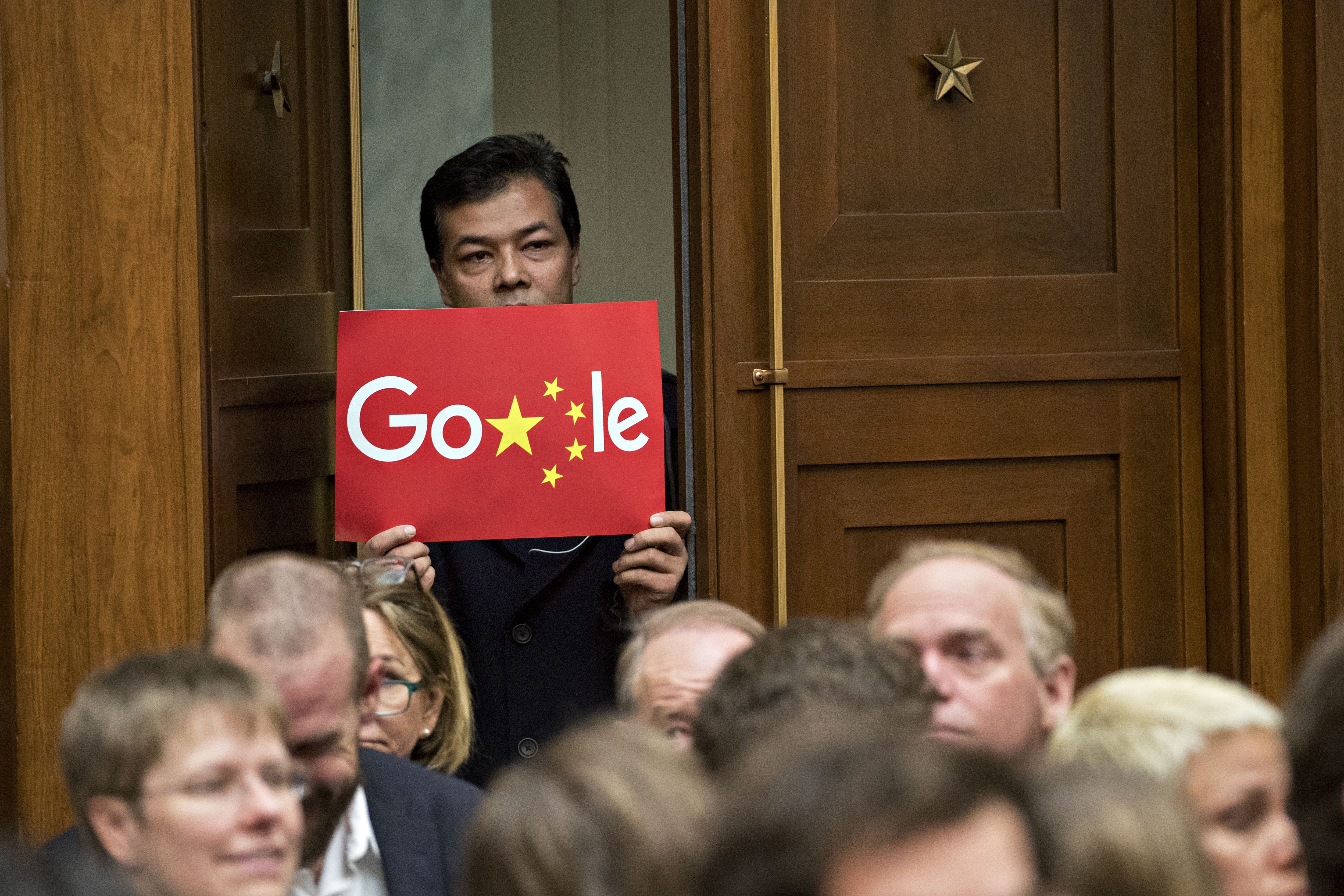 A man holds up a sign featuring an altered Google logo during a House Judiciary Committee hearing with Google CEO Sundar Pichai in Washington in December 2018. Photo: Bloomberg