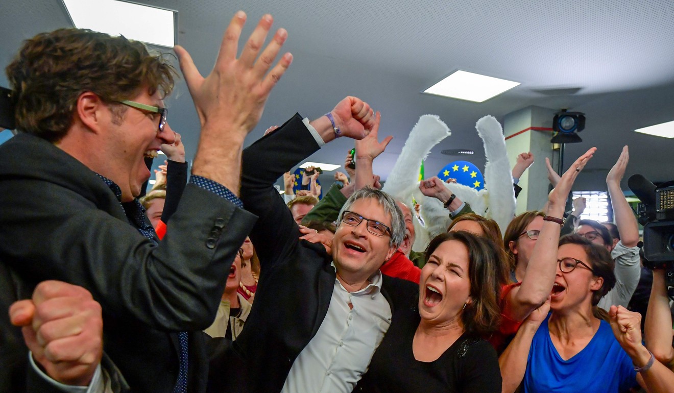 German Greens party top candidate Sven Giegold and co-leader of the Green party Annalena Baerbock celebrate as exit polls are announced. Photo: AFP
