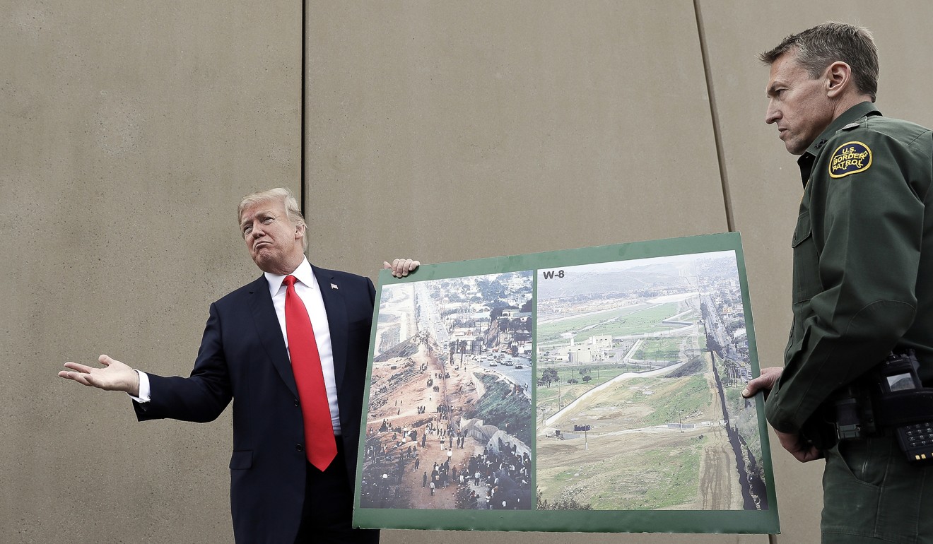 US President Donald Trump holds a poster with photographs of the US-Mexico border area in March 2018. Photo: AP