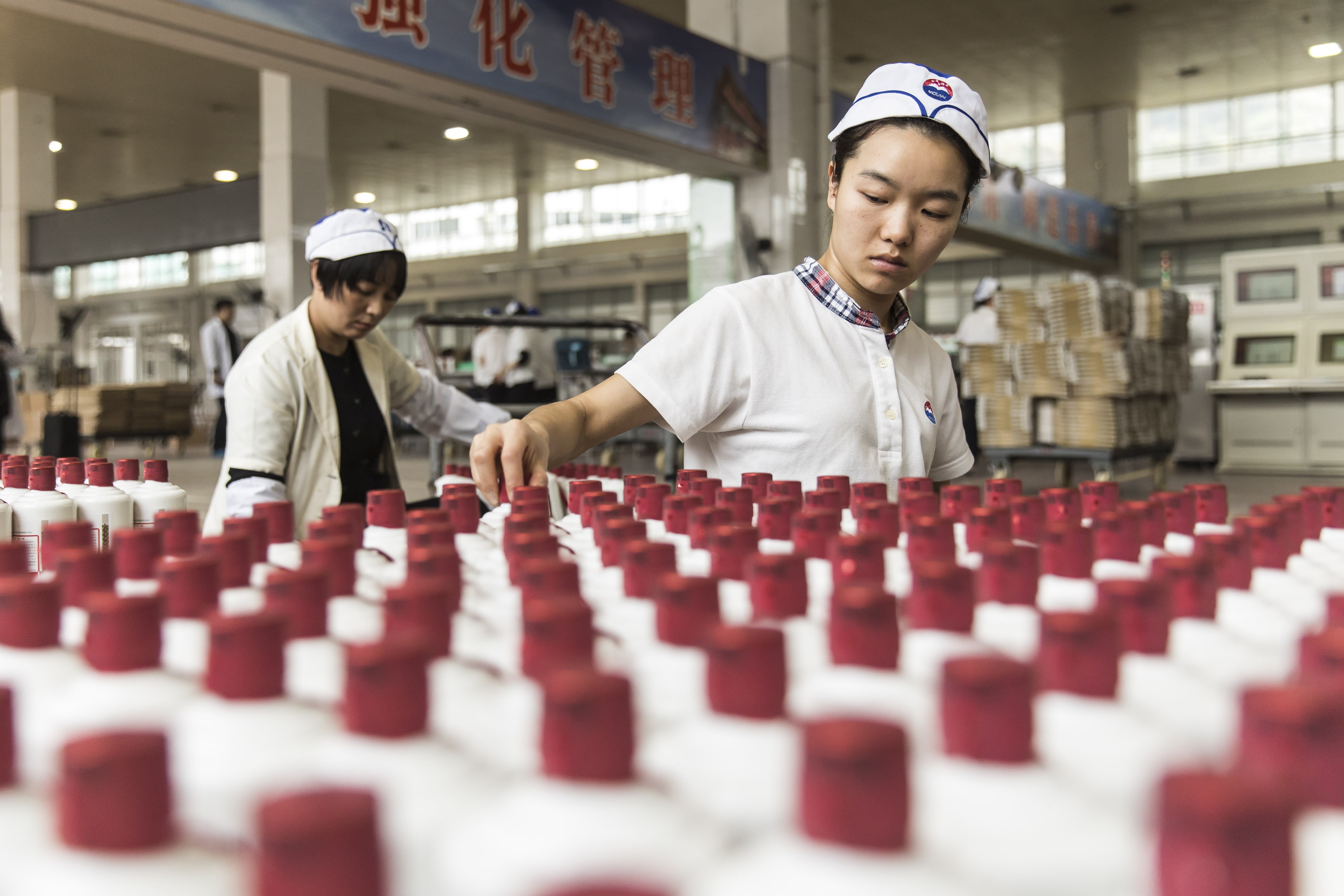 Employees arrange bottles of Moutai baijiu at the Kweichow Moutai factory in the town of Maotai in Renhuai, Guizhou province, China, on December 14, 2017.