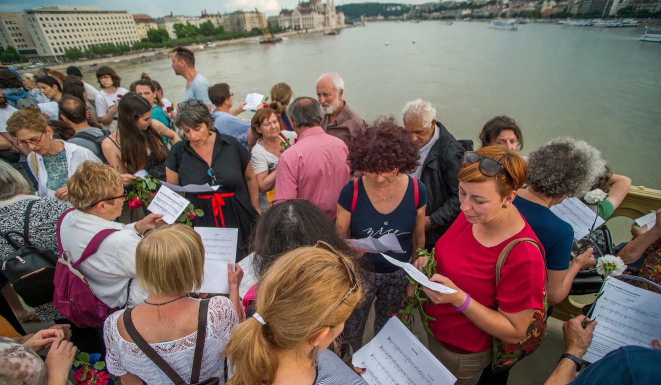 People sing the Korean folk song Arirang on Monday as they pay tribute to the victims of the capsized boat on the riverbank, next to Margaret Bridge in Budapest. Photo: EPA-EFE