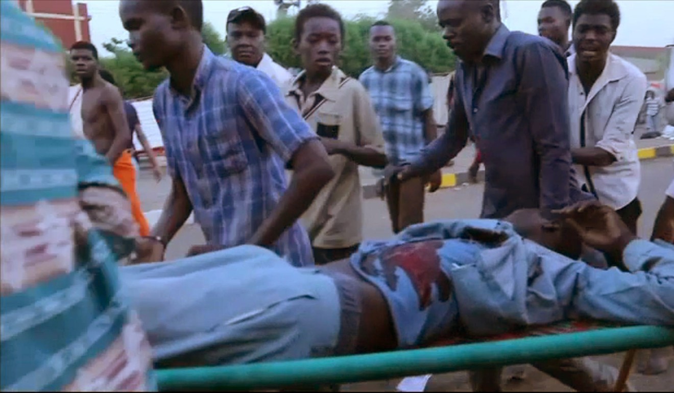 Sudanese protesters help a wounded man. Photo: AFP
