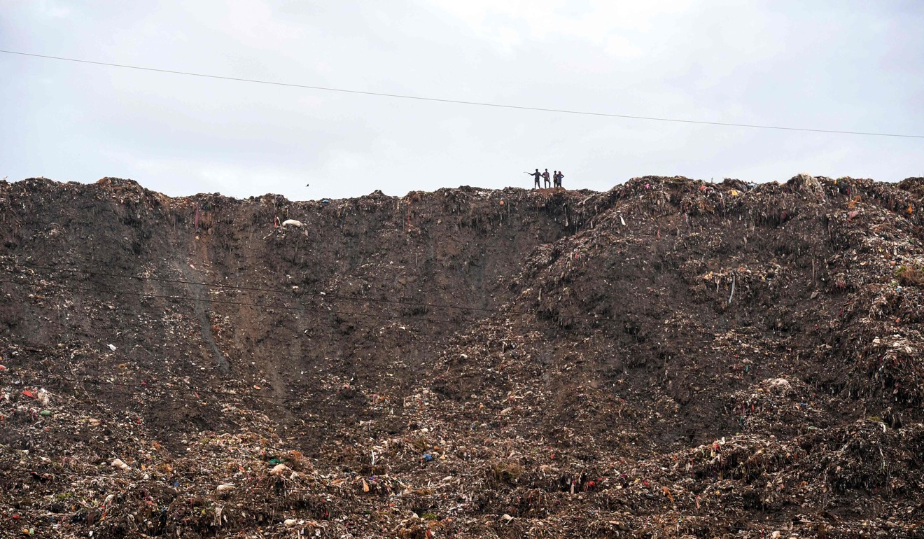 People stand atop the Ghazipur landfill after a section collapsed in 2017. Photo: AFP