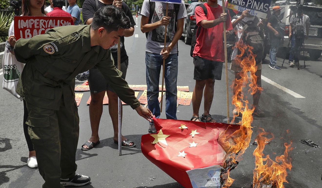 Protesters burn a mock Chinese flag during a rally outside the Chinese consulate in Manila. Photo: AP