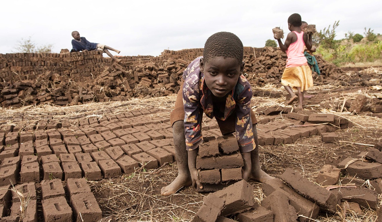 A boy lifts dry raw bricks and takes them to a kiln in central Malawi. Photo: AFP