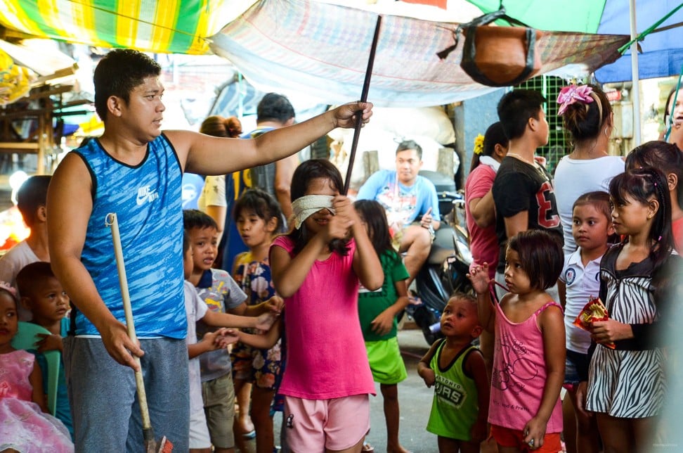 Blindfolded children enjoy taking turns in hitting a clay pot which is filled with confectionery. Photo: Maro Enriquez