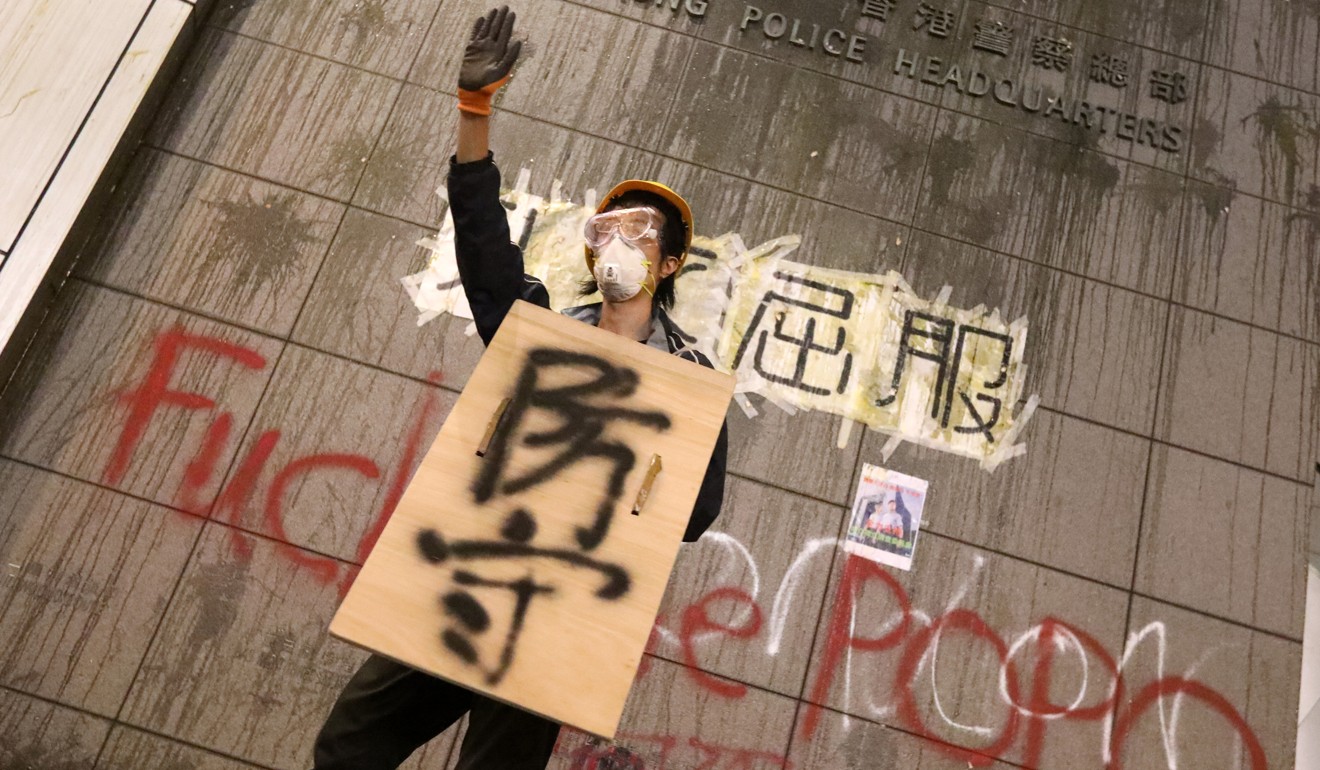 A protester stands in front of a wall at the police headquarters in Wan Chai, splattered with thrown eggs and graffiti. Photo: Felix Wong