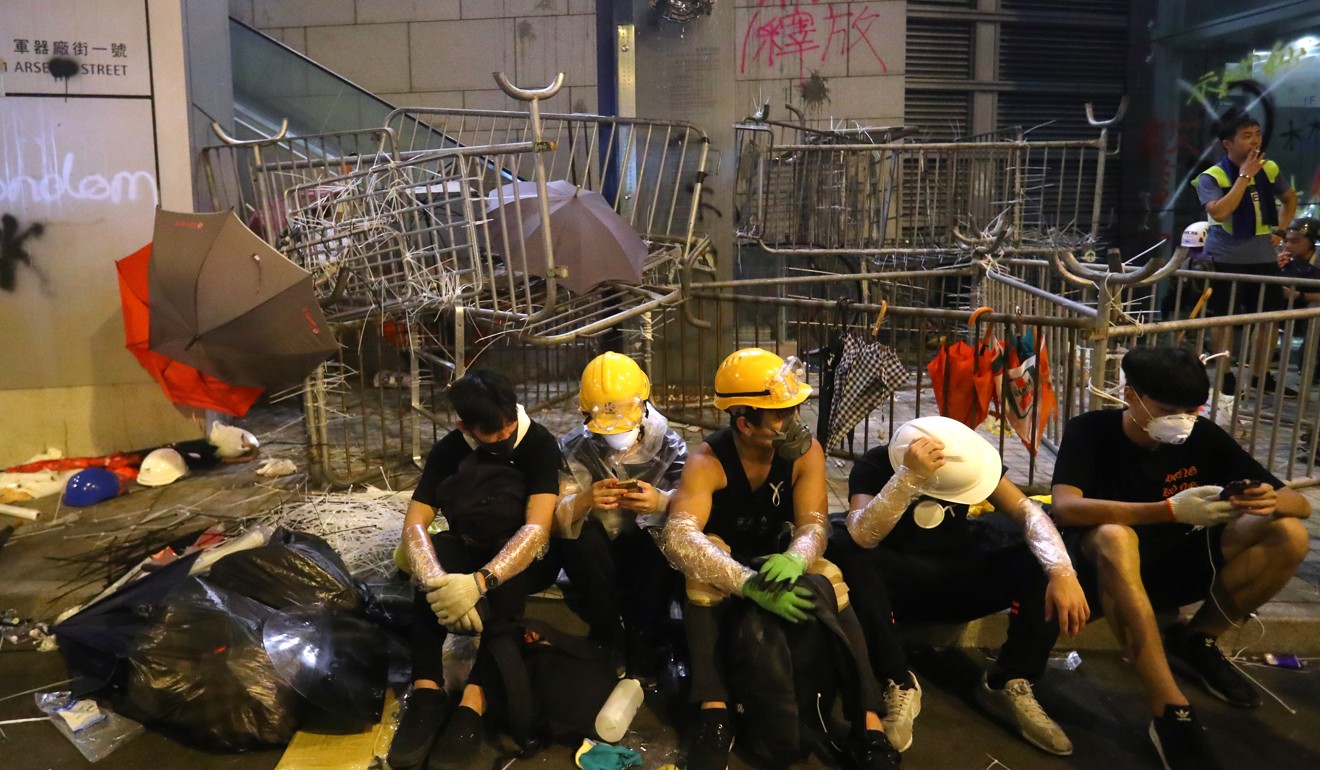 Demonstrators sitting in front of metal barricades stacked against exit points at police headquarters. Photo: Edmond So