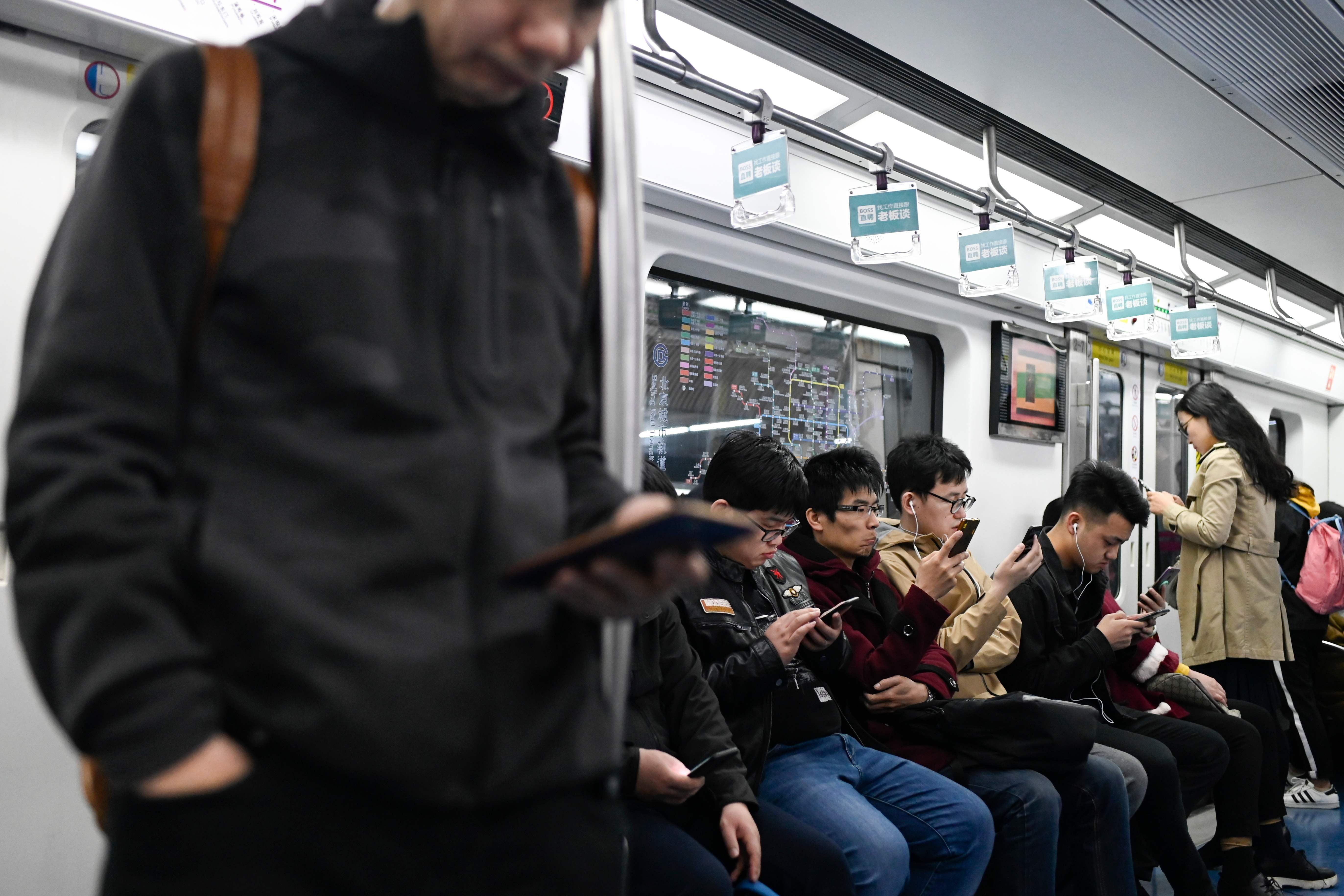 Commuters use their mobile phone as they ride on a subway in Beijing on April 8. While the mainland lags behind Hong Kong when it comes to smartphone penetration, it is far ahead in mobile payments. Photo: AFP