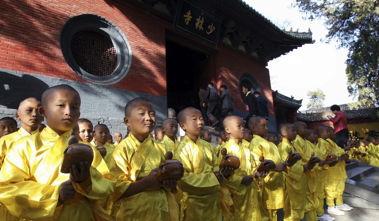 In this 2012 photo, visitors walk past as young monks offer prayers outside the Shaolin Temple. Photo: AP