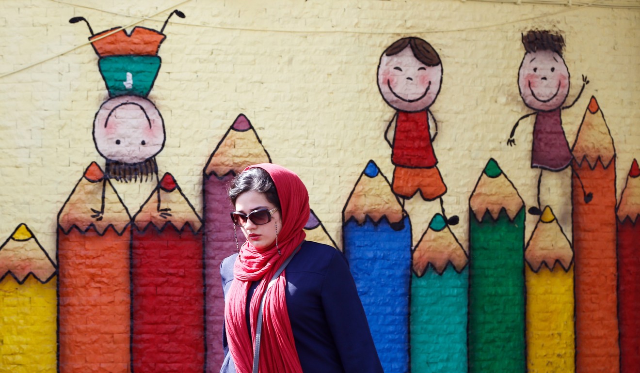 An Iranian woman walk past next to a wall painting in Tehran. Photo: EPA-EFE