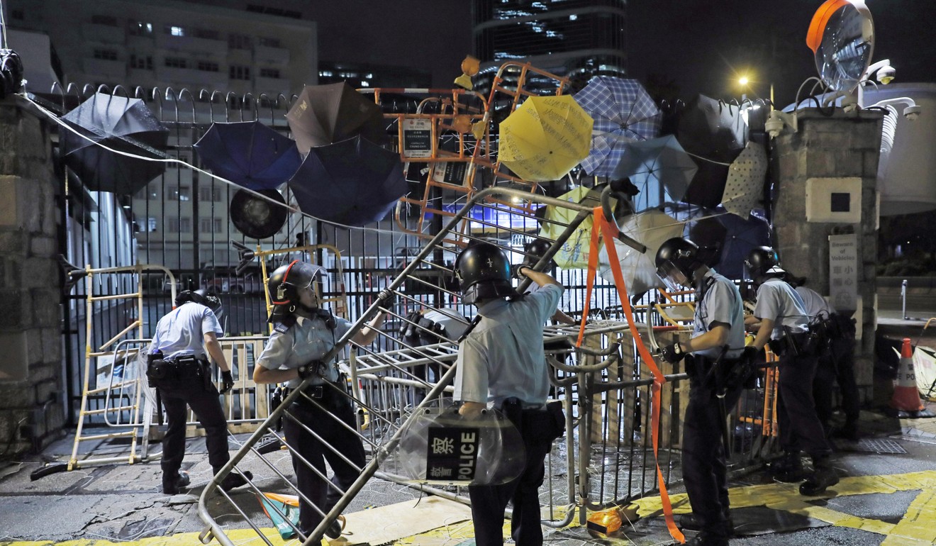 In the early hours of June 27, riot police clear away barricades erected by protesters outside police headquarters. Photo: AP