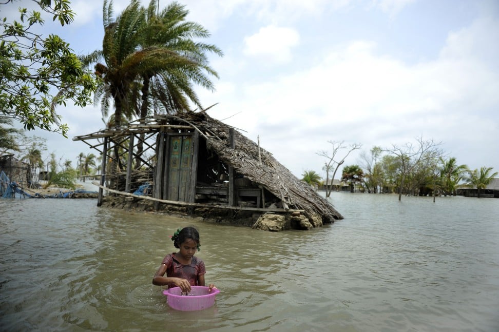 A child washes fish in front of a partially flooded home in Gabura, Bangladesh, in 2010. Cyclone Aila slammed into southern Bangladesh on May 26, 2009 but a year later the embankments destroyed in the storm had not been rebuilt, leaving land submerged. Photo: AFP