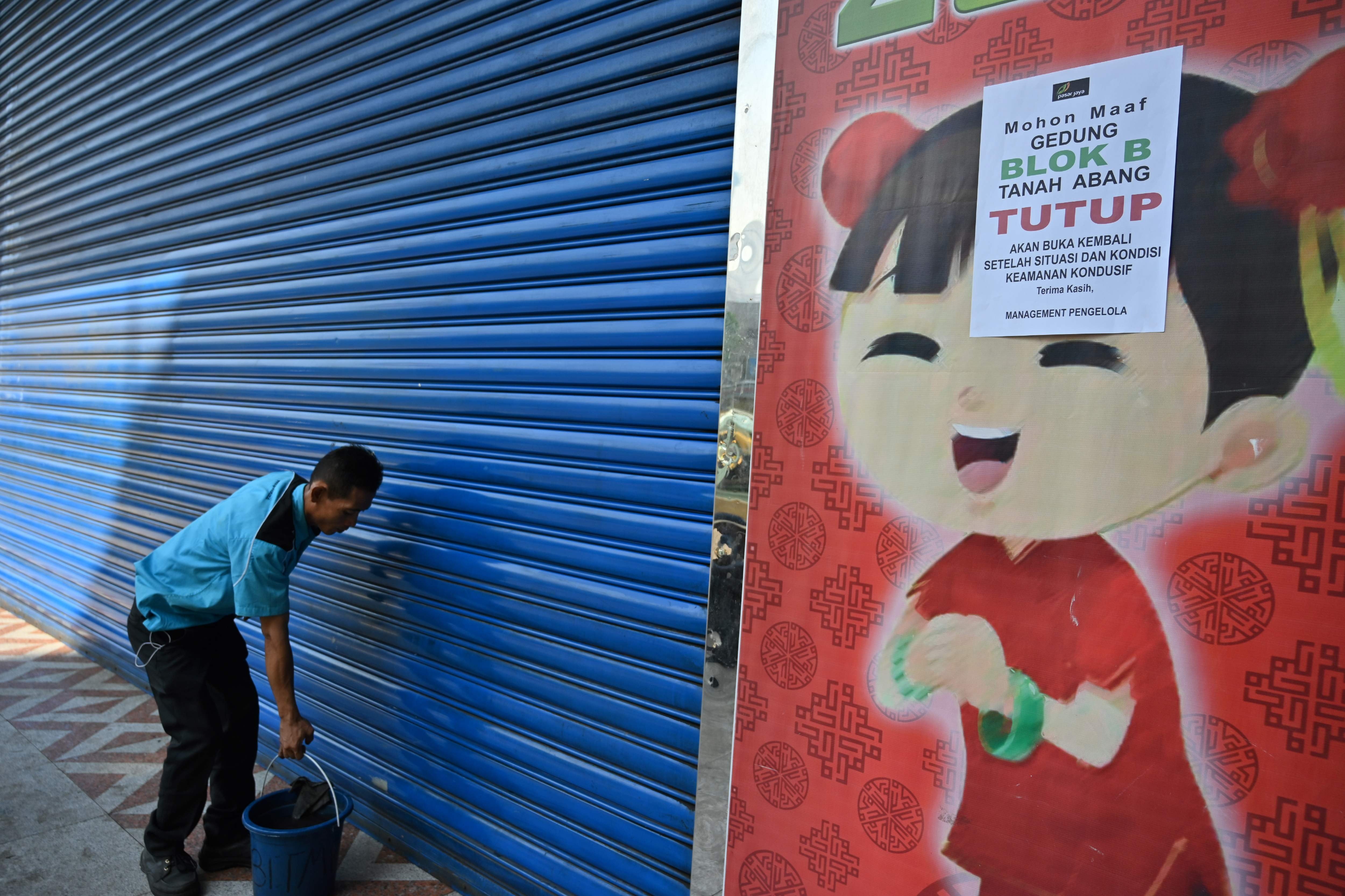 An Indonesian worker cleans the door of a market closed due to protests over the Indonesian election result. Photo: AFP