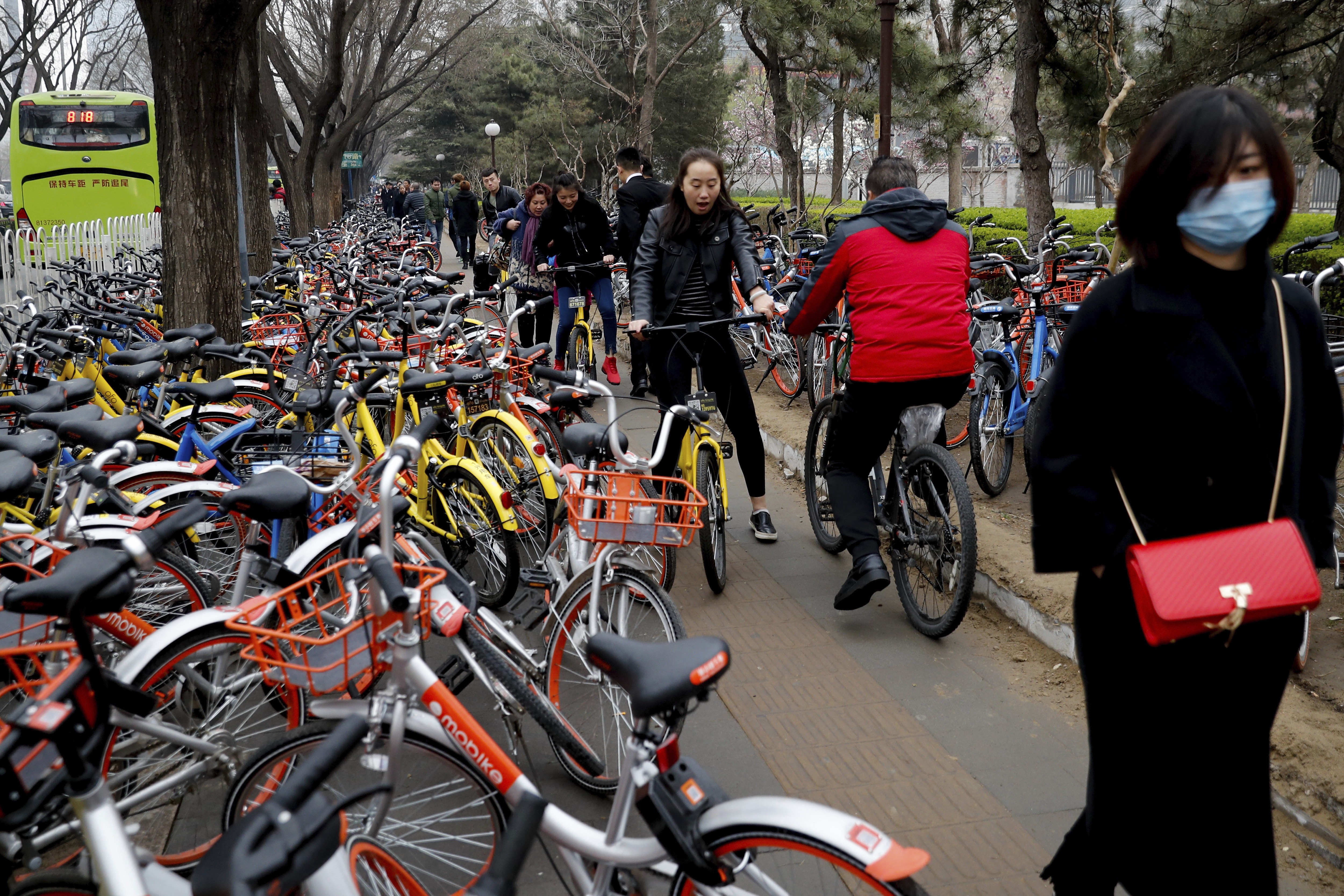A sidewalk crowded with bicycles from the bike-sharing companies Ofo, Mobike and Bluegogo, near a bus stand in Beijing, China. Photo: AP