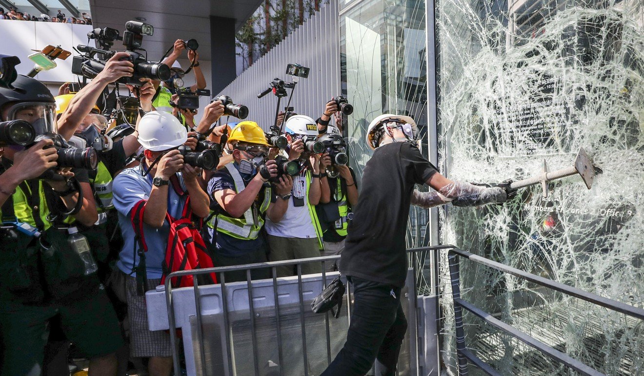 A protester smashes a window in Tamar on Monday before demonstrators entered the Legislative Council building. Photo: Sam Tsang