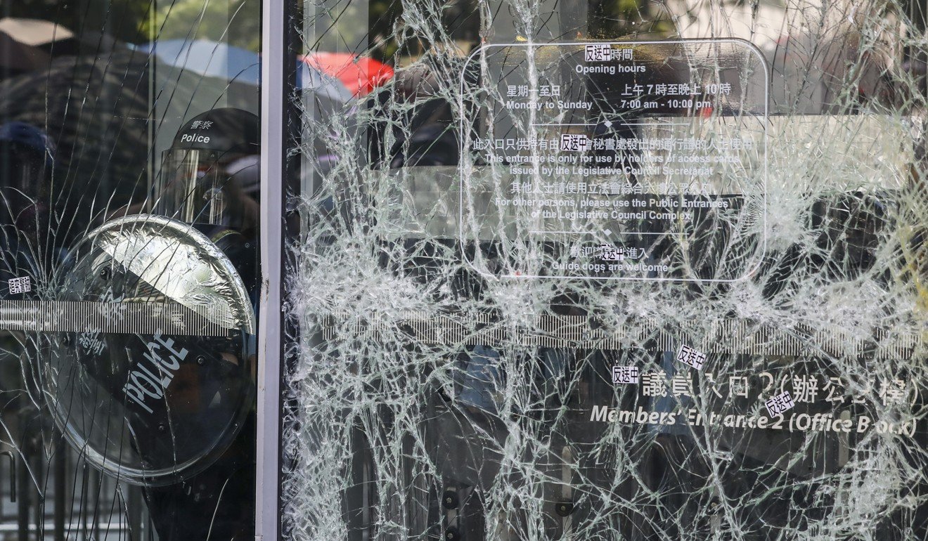 Riot police warn protesters as they smash windows of the Legislative Council complex in Tamar on Monday. Photo: Sam Tsang