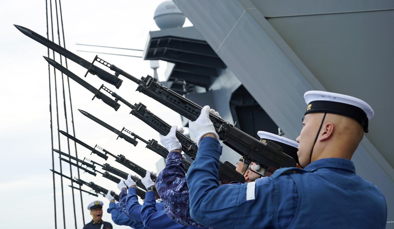 Troops aboard the Izumo aim their rifles towards the sky during a ceremonial rehearsal. Photo: AP