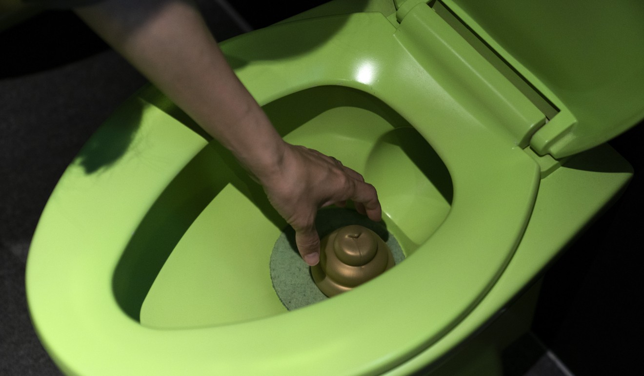A visitor reaches into a toilet bowl to pick up a toy poop at the Unko Museum in Yokohama. Photo: AP