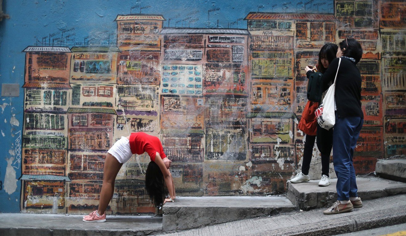 Tourists pose in front of a mural by graffiti artist Alex Croft on Graham Street in Central, a popular spot for photography. Photo: Winson Wong