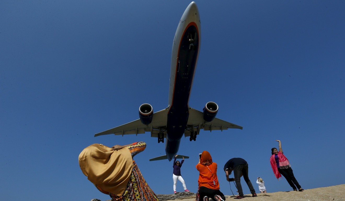 Tourists take pictures at Mai Khao Beach, as a plane approaches the Phuket International Airport. File photo: Reuters
