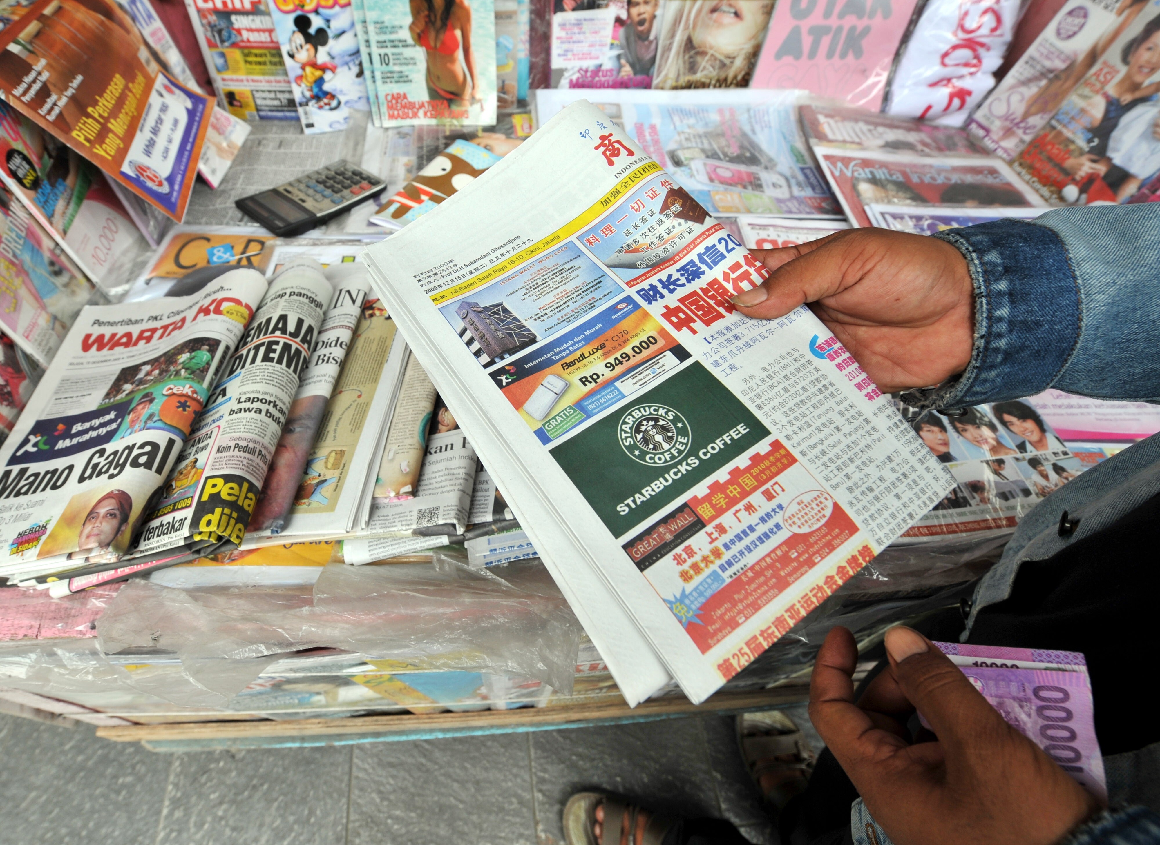 An Indonesian stallholder with a Chinese-language newspaper in Jakarta. Photo: AFP