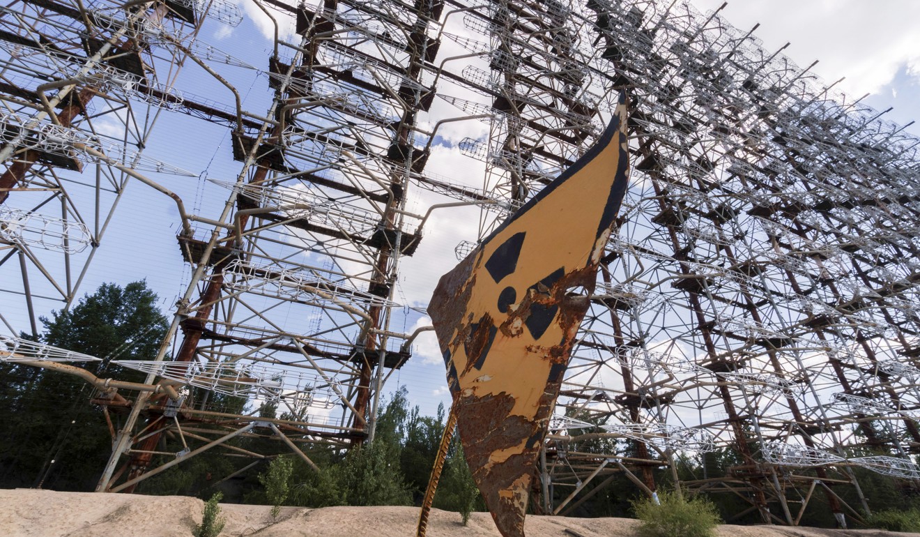 A rusty radioactivity warning sign sits beneath the inter-ballistic early warning radar system, known as Duga Radar, in the Chernobyl exclusion zone in June. Photo: Bloomberg