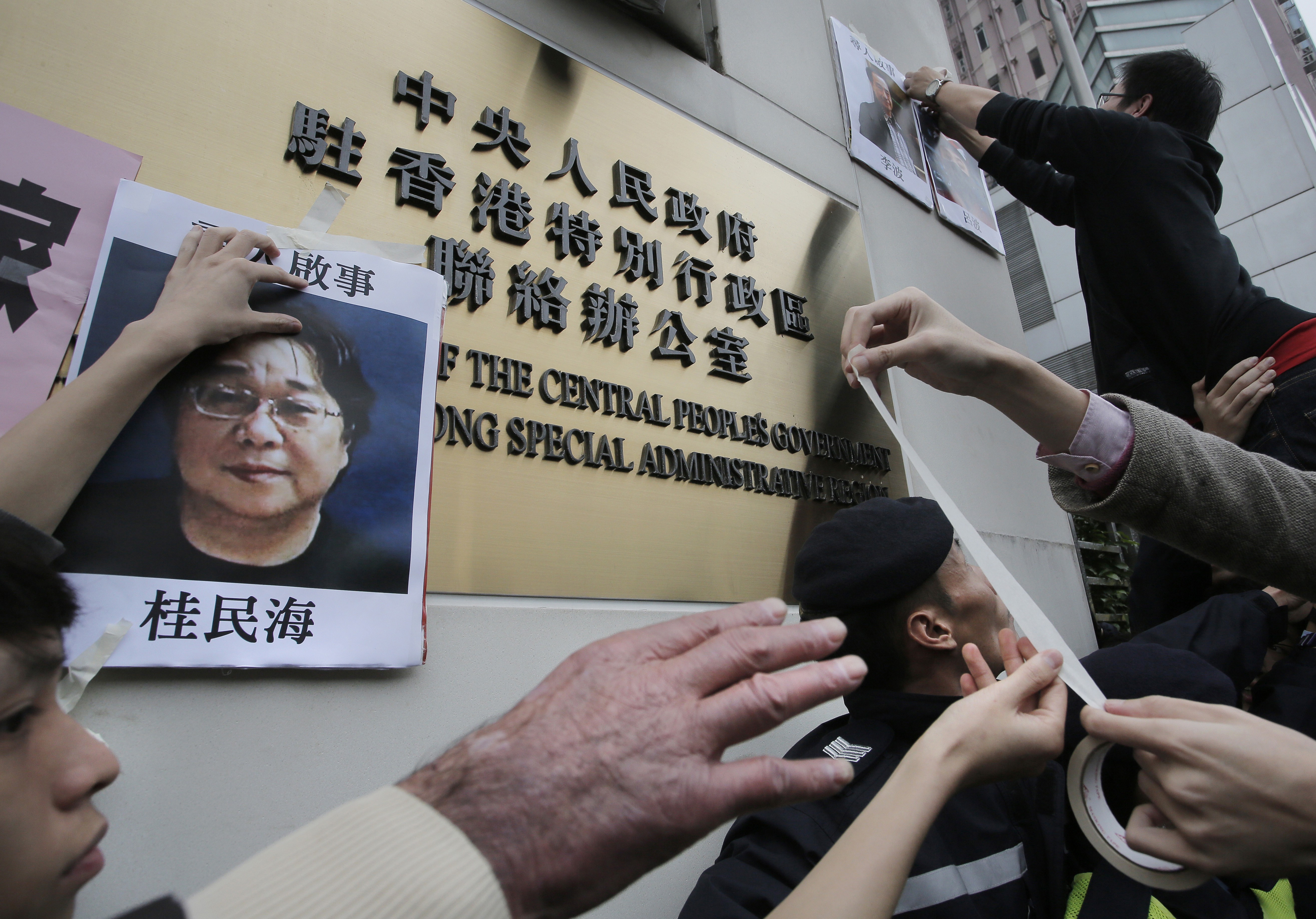 Protesters try to stick photos of missing booksellers, one of which shows Gui Minhai (left), during a demonstration outside the mainland Liaison Office in Hong Kong, on January 3, 2016. Gui, a Swedish citizen, was one of five employees of a Hong Kong bookshop specialising in salacious tales about high-level Chinese politics who were believed to have been spirited to the mainland in late 2015. Photo: AP
