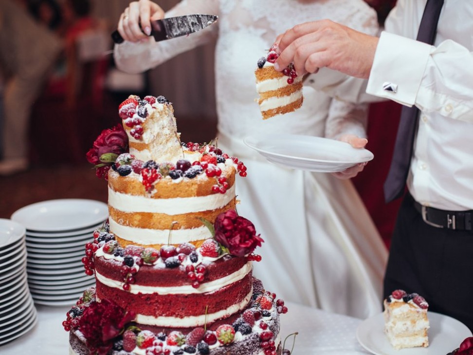 A couple cut their wedding cake for guests at their wedding banquet. Photo: Shutterstock
