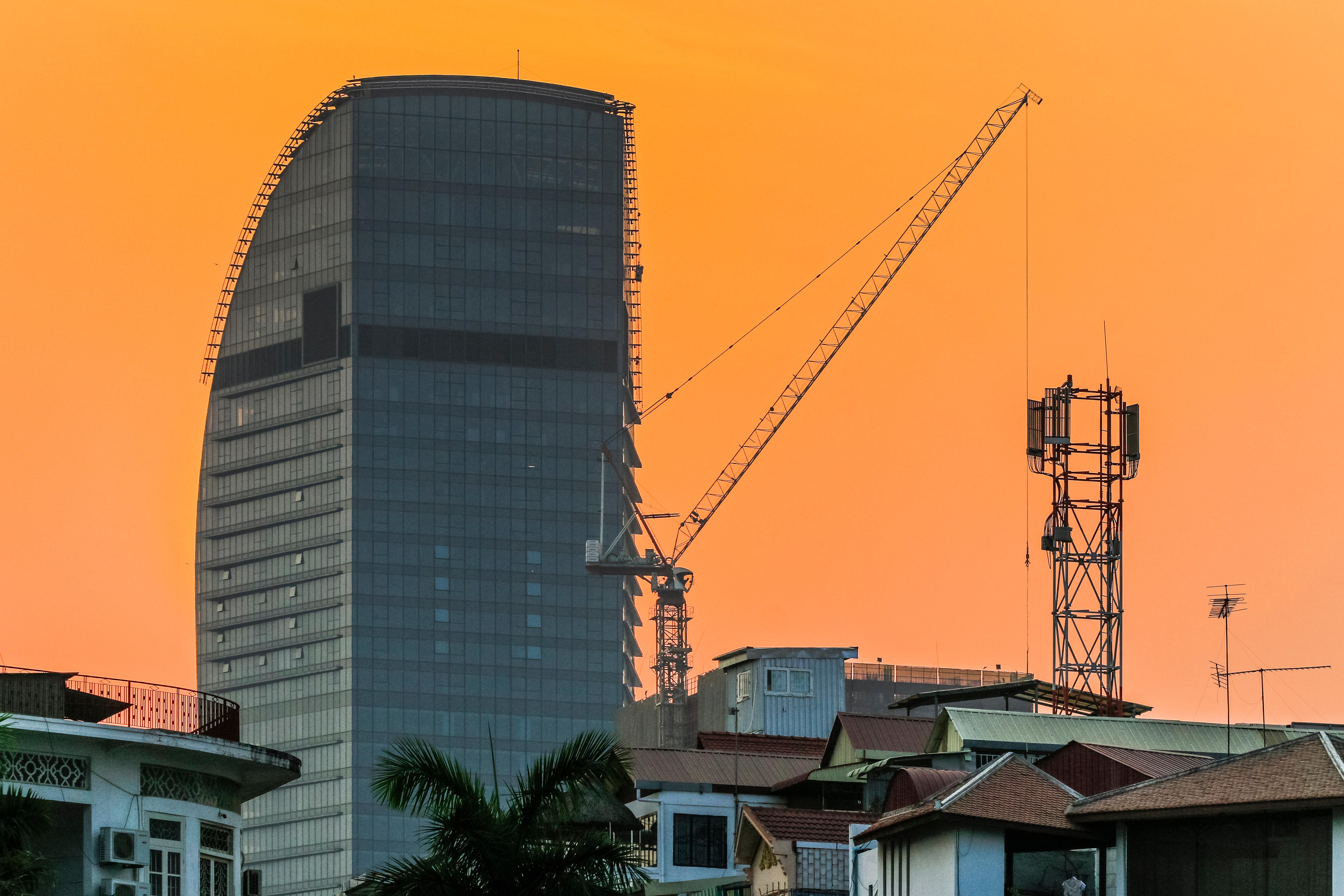 A modern tower block and crane loom over older buildings in central Phnom Penh, Cambodia. Photo: Alamy