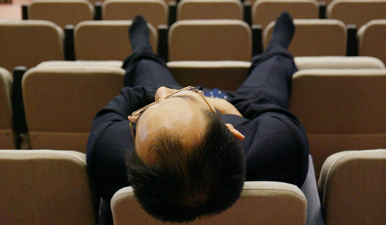A Japanese businessman takes a nap during the preview of Tokyo Motor Show in October 2003. Photo: AFP
