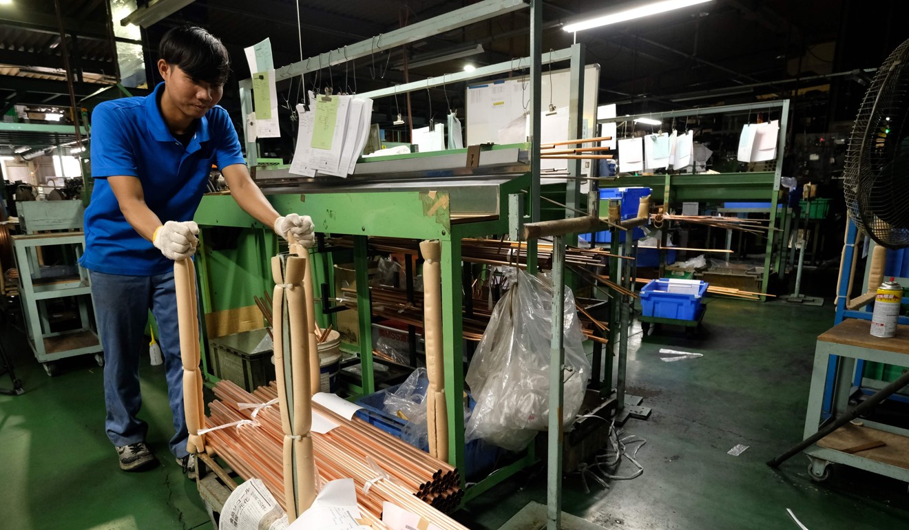 An Indonesian worker moving copper tubes at a factory in Oizumi. Photo: AFP