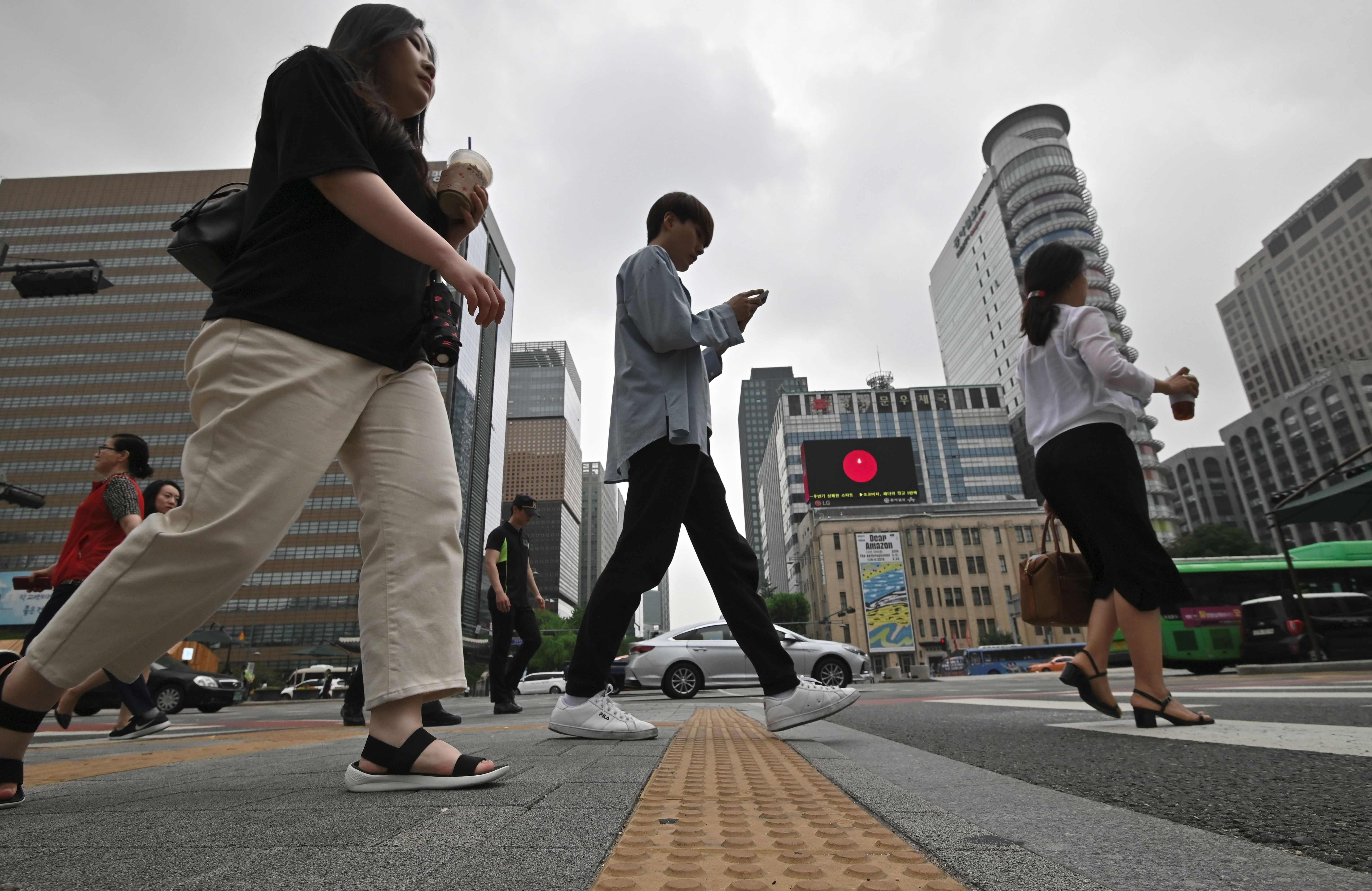 Pedestrians cross a road in a business district in Seoul. Photo: AFP