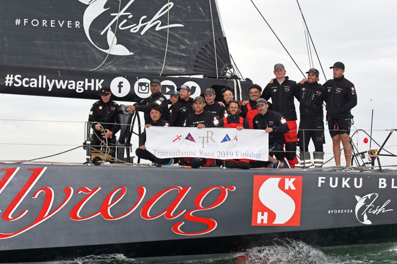 The Scallywag crew pose on the deck of their super maxi 100-footer after taking line honours in the Transatlantic Race 2019. Photo: Rick Tomlinson