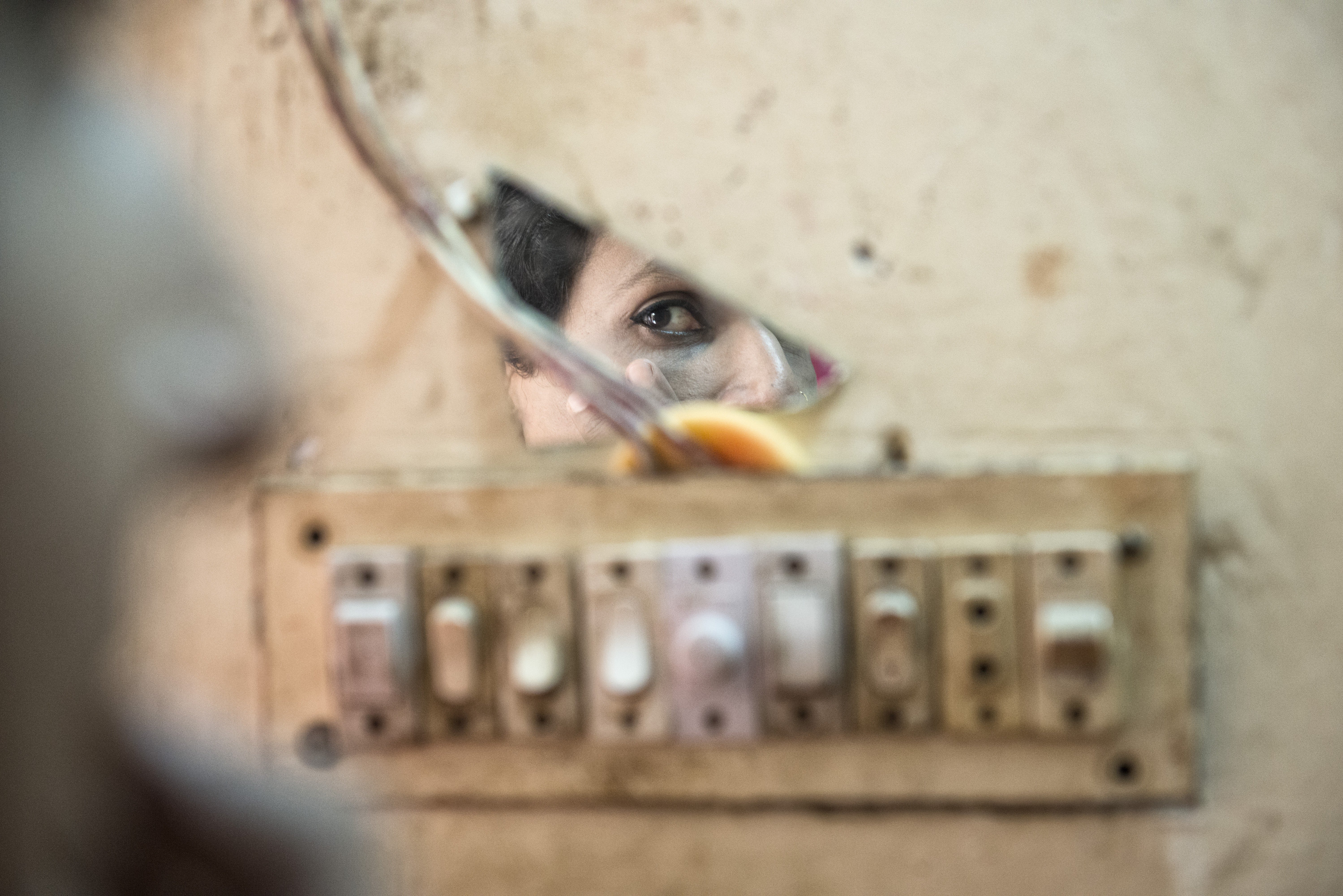 Shanta, a hijra from Bangladesh, applies her make-up in front of a fragment of mirror in the attic she rents with other transgenders. Photo: Zigor Aldama