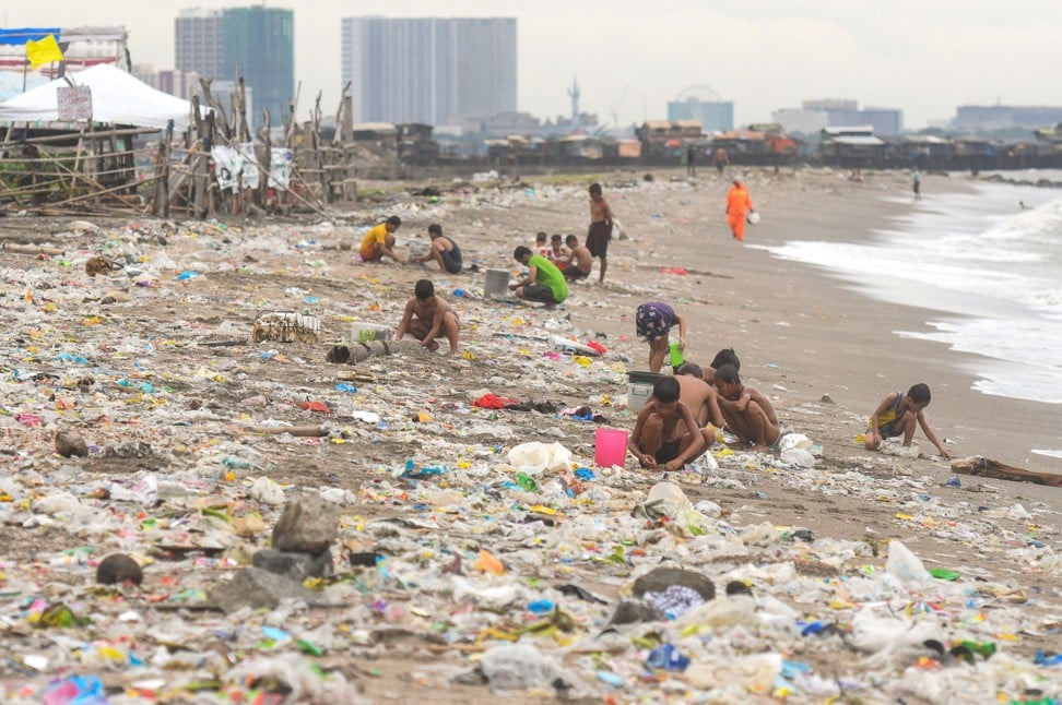 People collect rubbish on a beach in Manila. Photo: NurPhoto