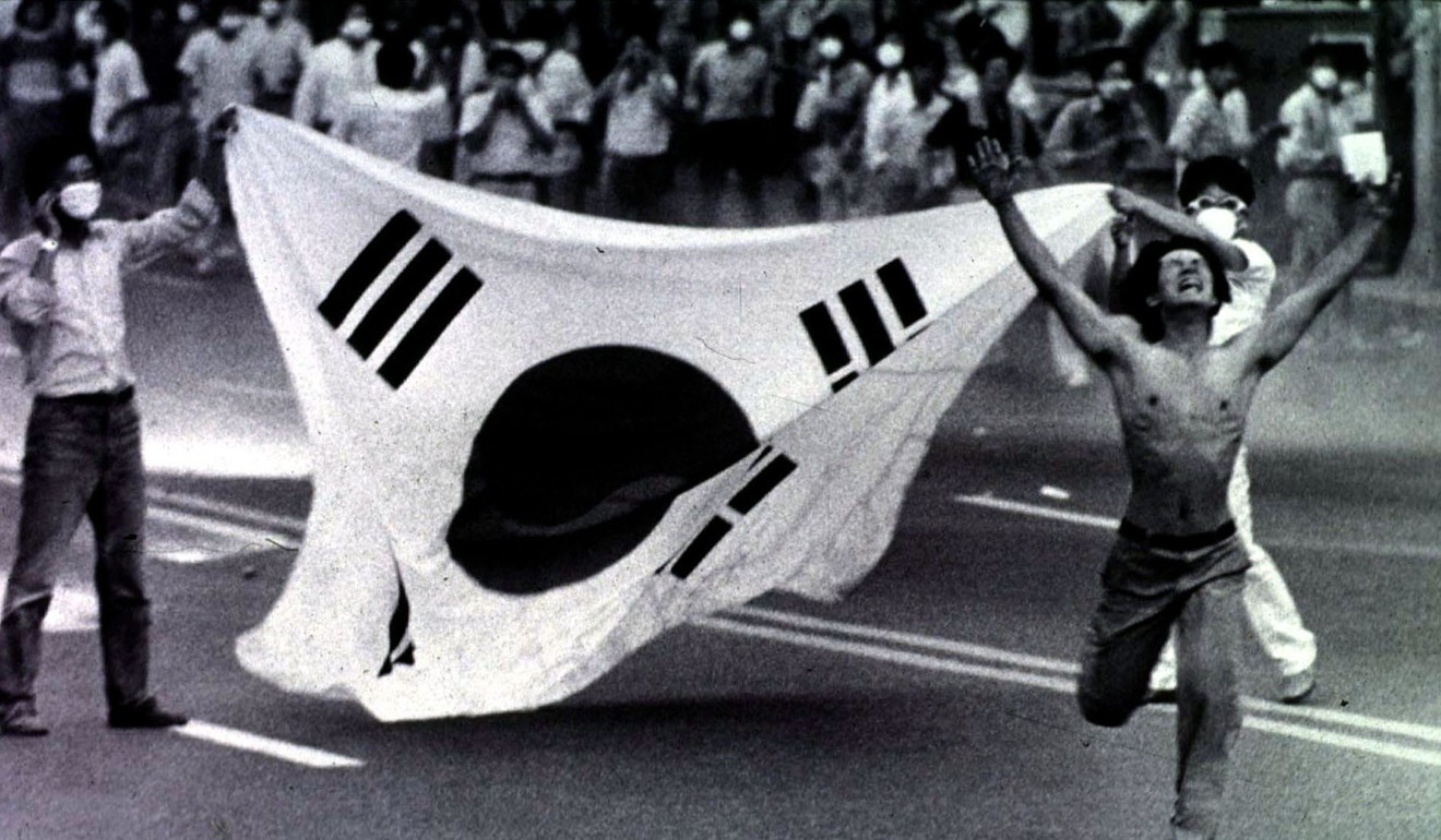 A protester rushes toward riot police after shouting “Don't shoot tear gas” while others raise a South Korean flag during a peaceful anti-government demonstration in Pusan City, Korea in 1987. That August, government and opposition officials agreed to revise the constitution to clear the way for direct presidential elections and other reforms. Photo: AP