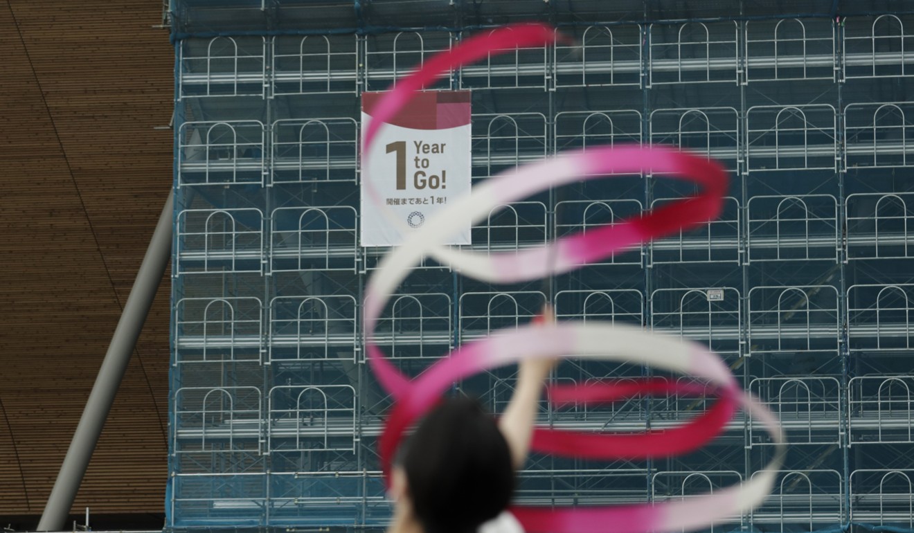 A gymnast performs in front of a ‘1-Year to Go’ banner outside the Ariake Gymnastics Centre in Tokyo on July 22. Photo: AP