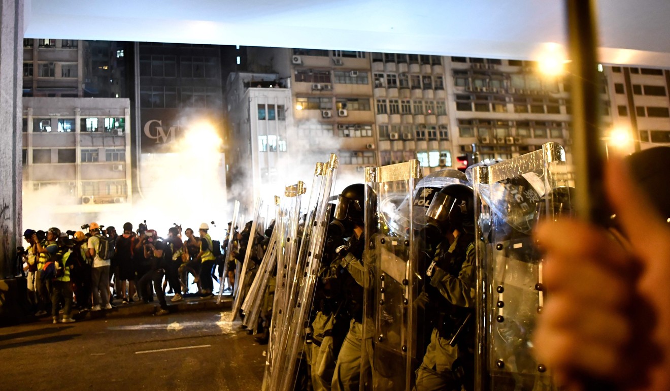 Riot police lined up as tear gas is fired during a protest outside Beijing’s liaison office in Sai Ying Pun on July 21. Photo: AFP