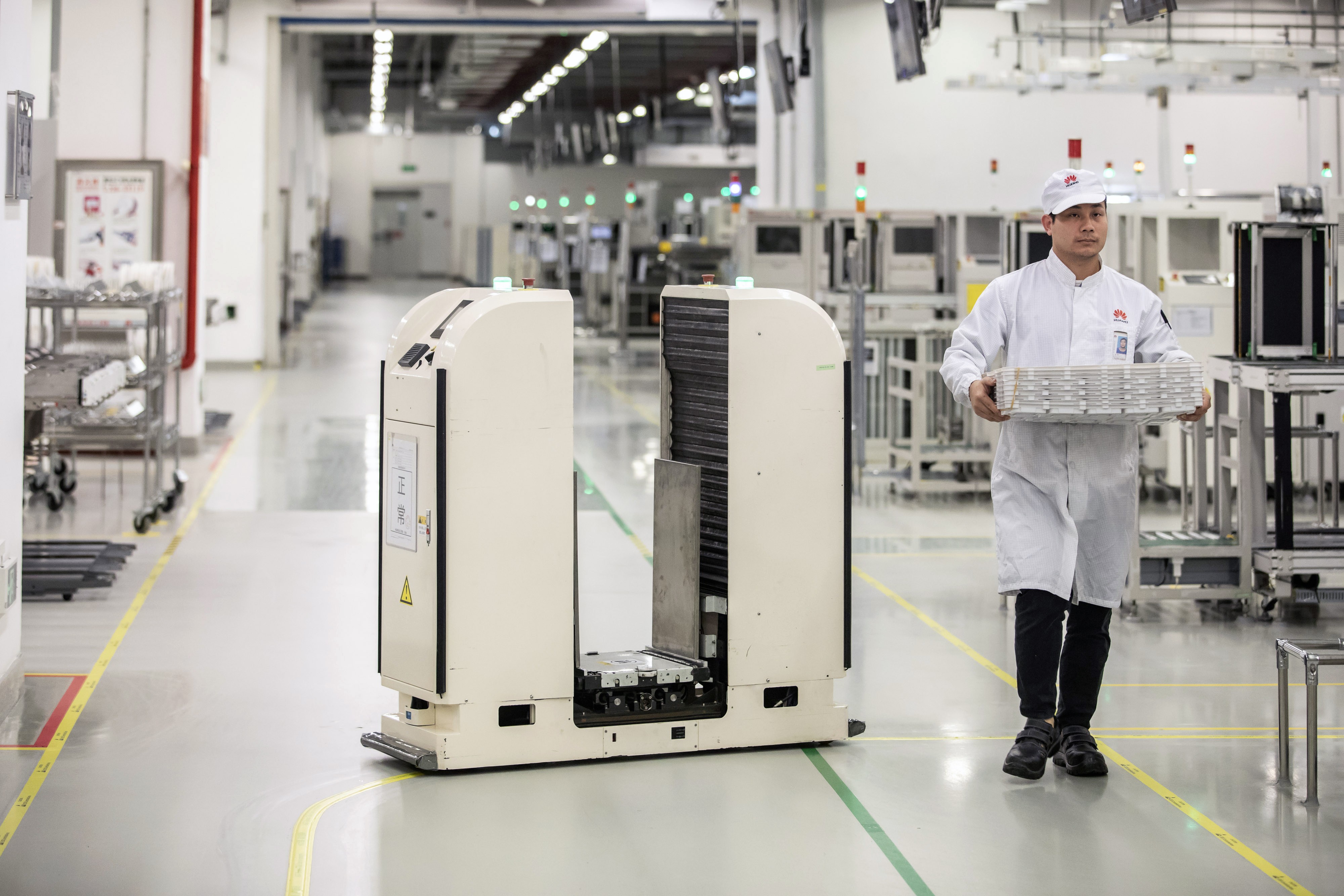 A robot passes an employee working on a mobile phone assembly line at a Huawei Technologies production base in Dongguan, China, on Wednesday, March 6, 2019. Photo: Bloomberg