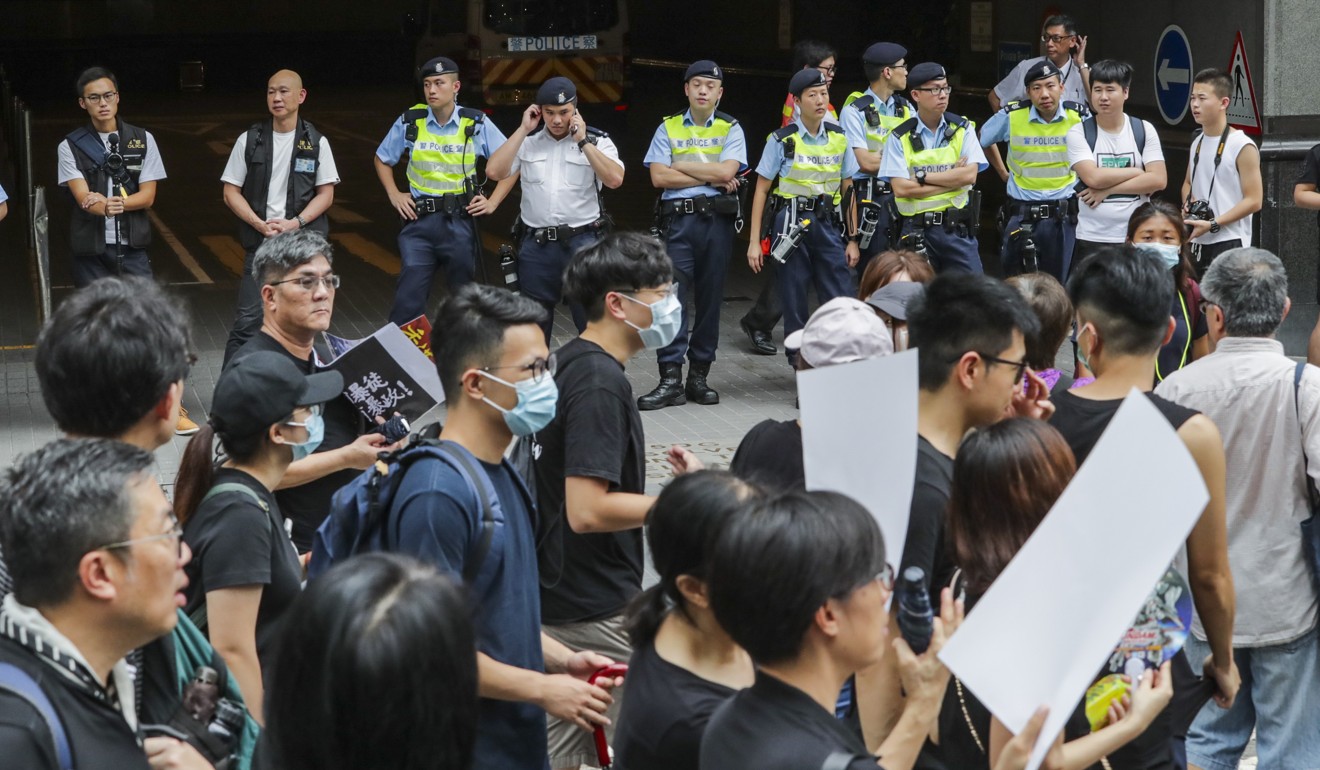 Police officers look on as people take part in an extradition bill march in Tsim Sha Tsui. Photo: Edmond So