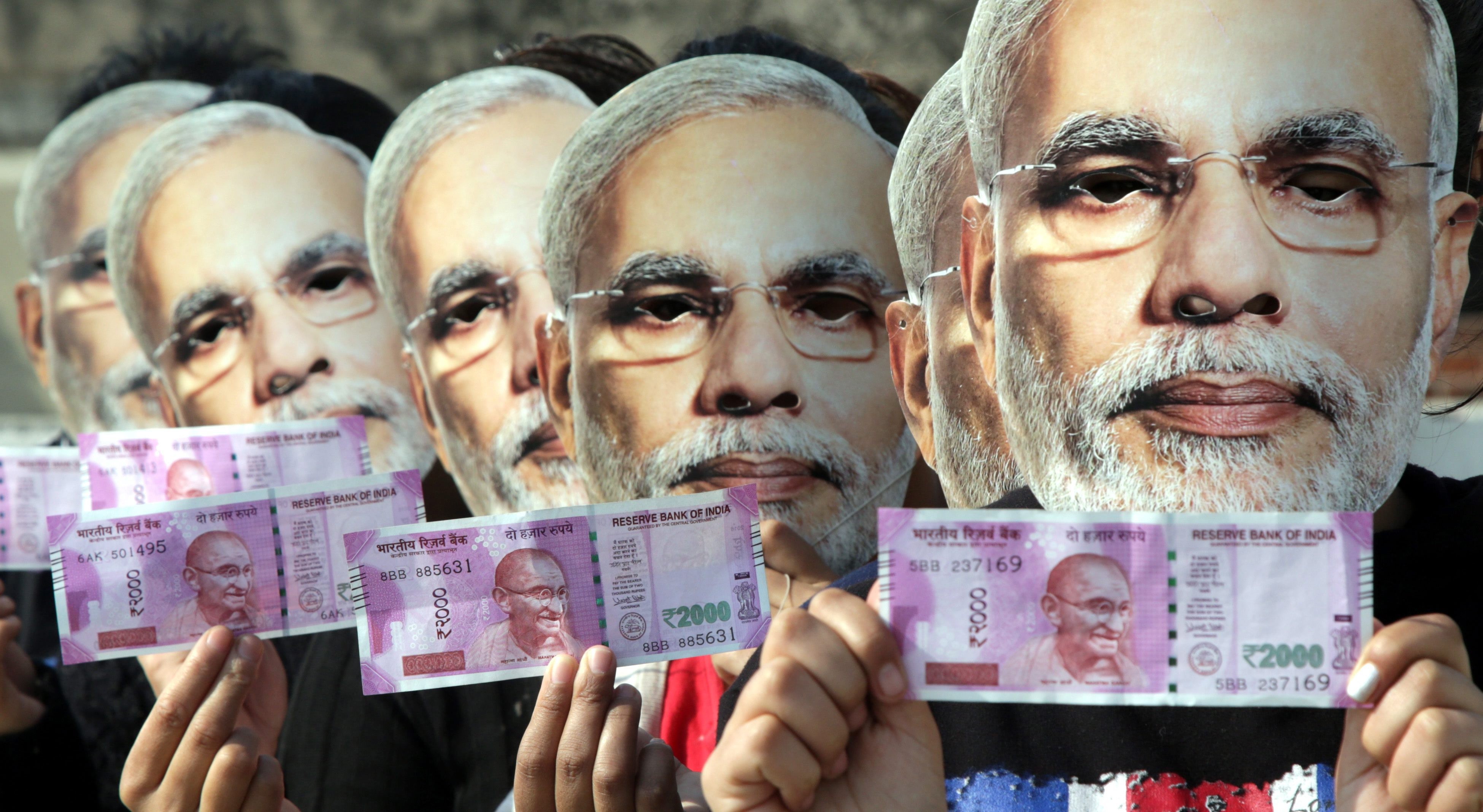 Indian girls wear masks depicting Indian Prime Minister Narendra Modi and hold up new currency notes in November, 2016. Photo: EPA