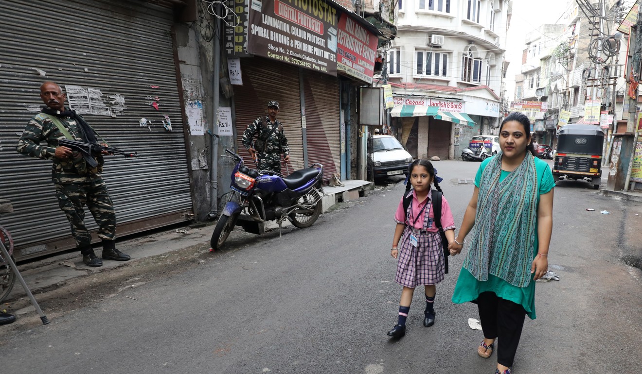 Indian paramilitary soldiers stand guard as a woman and her child walk toward a school in Kashmir. Photo: EPA-EFE