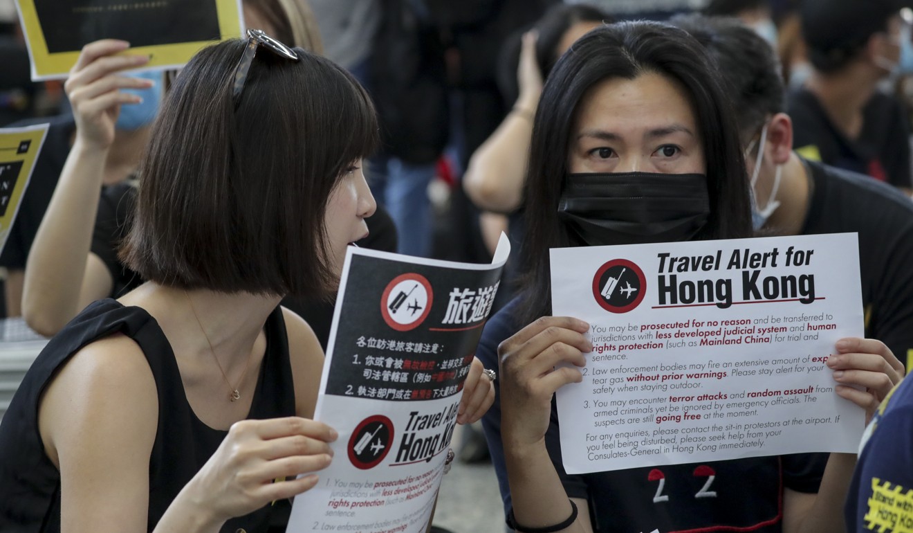 Protesters hold posters aloft in Hong Kong airport’s arrival hall outlining their demands in front of international travellers. Photo: Edmond So