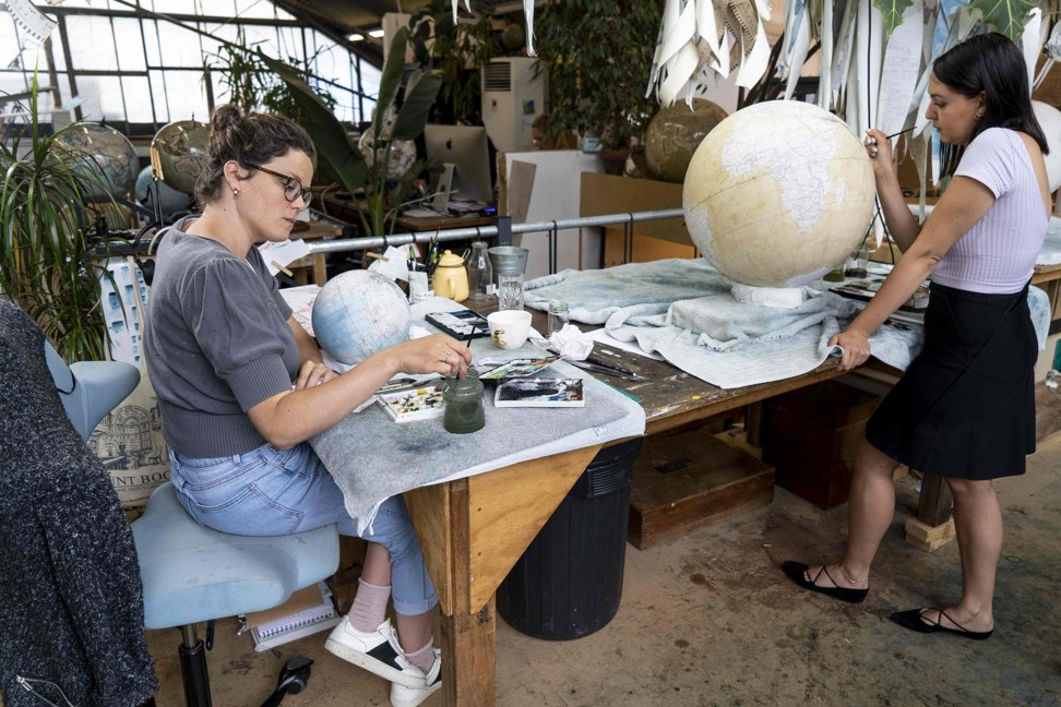 Artists applying paintwork to globes. Photo: AFP