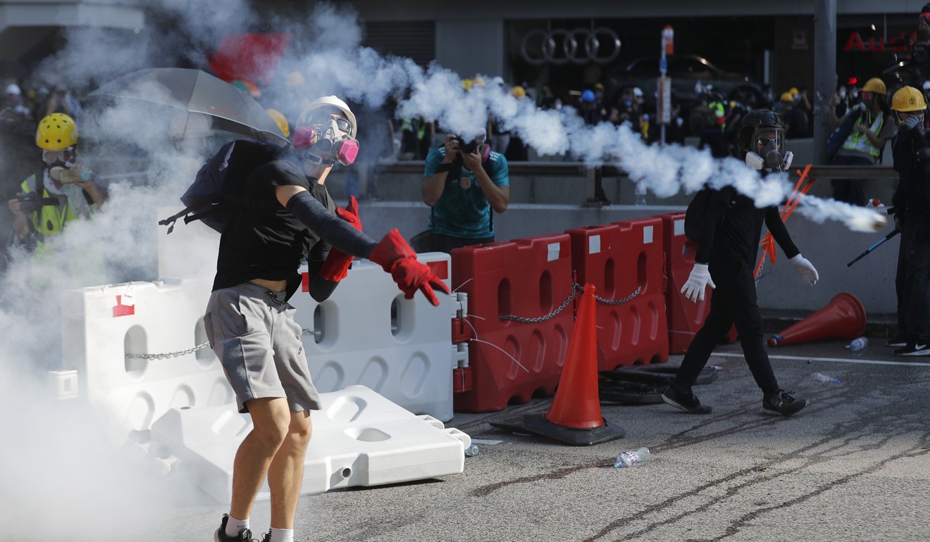 A protester throws back a tear-gas canister during demonstrations in Hong Kong. Photo: AP