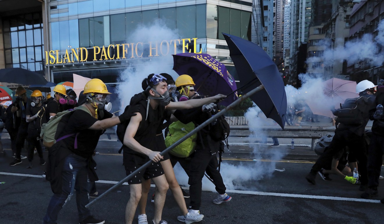 Protesters use umbrellas to shield themselves from tear gas fired by policemen as they face off on a streets in Hong Kong. Photo: AP