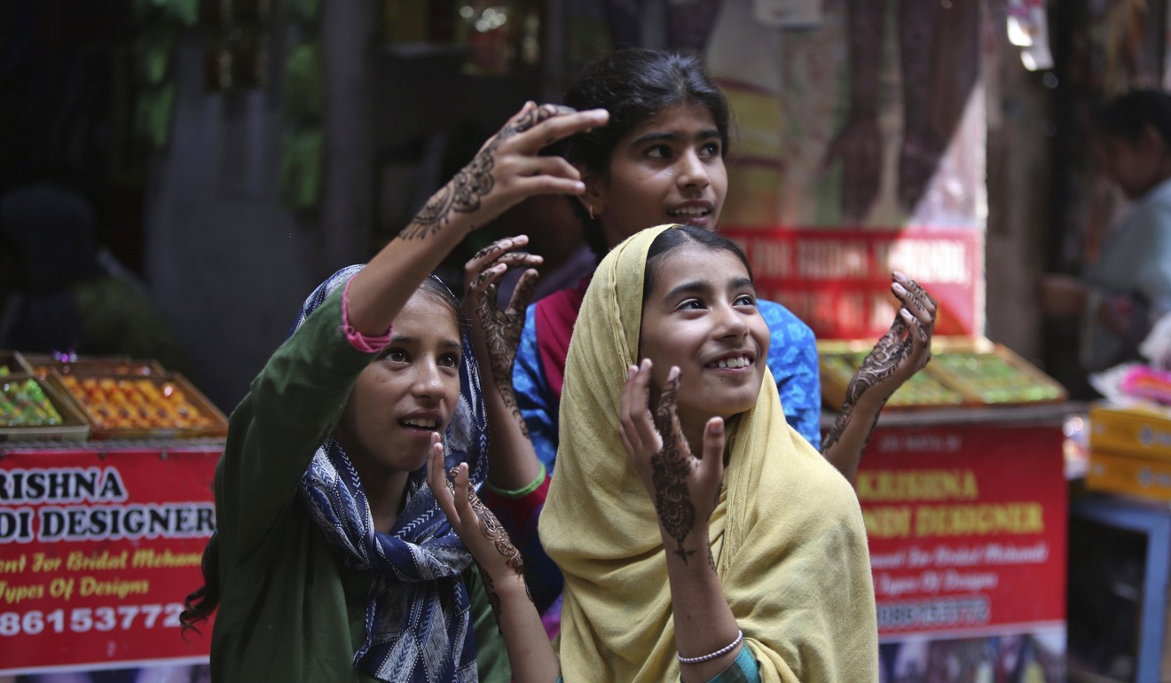 Girls gesture after getting henna decorations on their hands on the eve of Eid al Adha, in Jammu, India. Photo: AP Photo